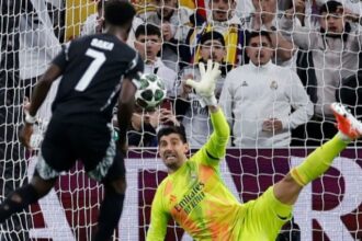 Real Madrid’s Belgian goalkeeper #01 Thibaut Courtois stops the ball as Arsenal’s English midfielder #07 Bukayo Saka shoots from the penalty spot during the UEFA Champions League quarter final second leg football match between Real Madrid CF and Arsenal at Santiago Bernabeu Stadium in Madrid on April 16, 2025. (Photo by OSCAR DEL POZO / AFP)