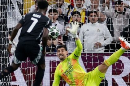 Real Madrid’s Belgian goalkeeper #01 Thibaut Courtois stops the ball as Arsenal’s English midfielder #07 Bukayo Saka shoots from the penalty spot during the UEFA Champions League quarter final second leg football match between Real Madrid CF and Arsenal at Santiago Bernabeu Stadium in Madrid on April 16, 2025. (Photo by OSCAR DEL POZO / AFP)