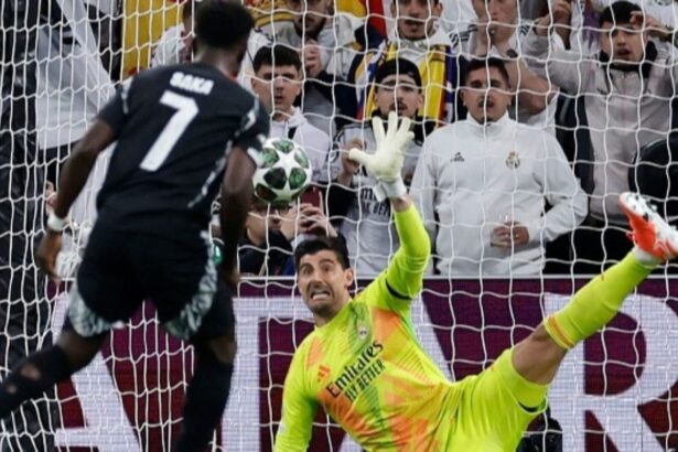 Real Madrid’s Belgian goalkeeper #01 Thibaut Courtois stops the ball as Arsenal’s English midfielder #07 Bukayo Saka shoots from the penalty spot during the UEFA Champions League quarter final second leg football match between Real Madrid CF and Arsenal at Santiago Bernabeu Stadium in Madrid on April 16, 2025. (Photo by OSCAR DEL POZO / AFP)