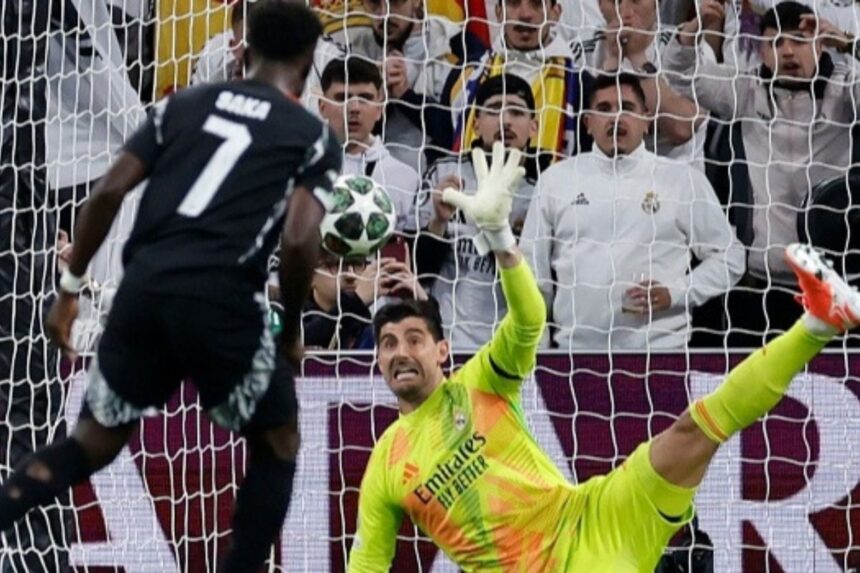 Real Madrid’s Belgian goalkeeper #01 Thibaut Courtois stops the ball as Arsenal’s English midfielder #07 Bukayo Saka shoots from the penalty spot during the UEFA Champions League quarter final second leg football match between Real Madrid CF and Arsenal at Santiago Bernabeu Stadium in Madrid on April 16, 2025. (Photo by OSCAR DEL POZO / AFP)